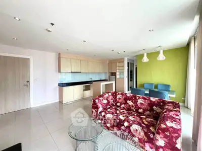 Spacious modern living room with open kitchen and floral sofa in a bright apartment