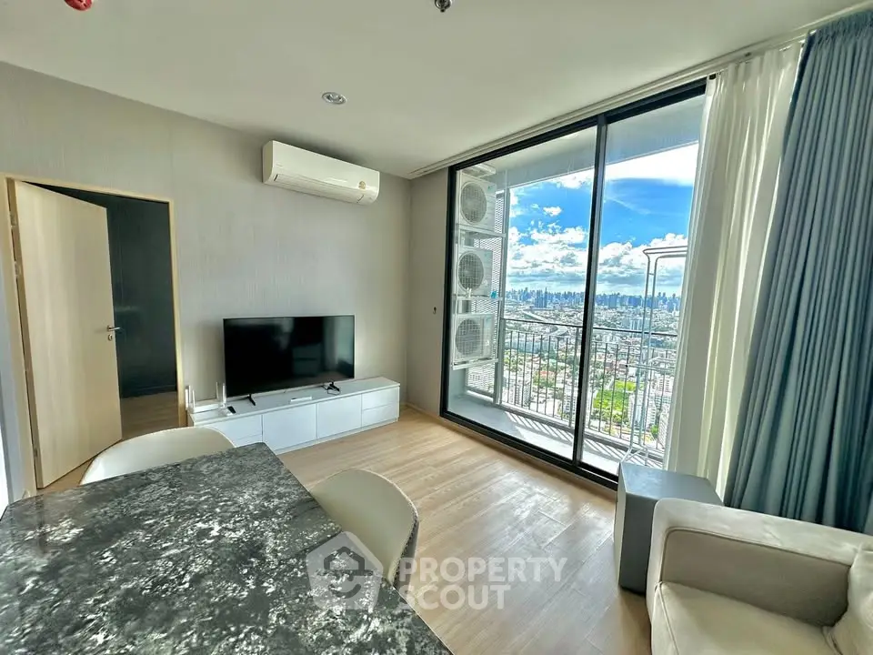 Modern living room with city view and balcony access in high-rise apartment