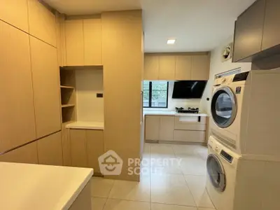 Modern kitchen with sleek cabinetry and built-in laundry appliances in a spacious layout.