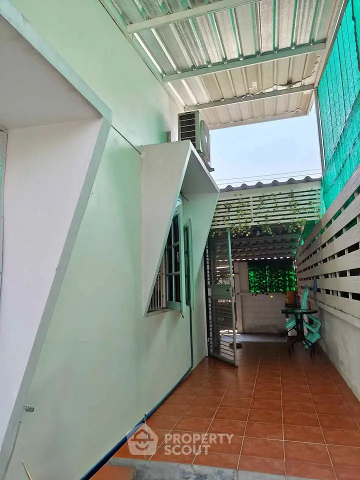 Charming covered outdoor patio with tiled flooring and seating area, perfect for relaxation.
