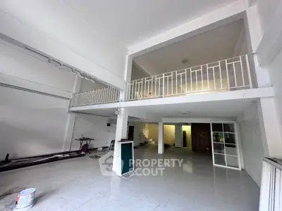 Spacious industrial-style interior with high ceilings and mezzanine, perfect for creative workspace or studio.