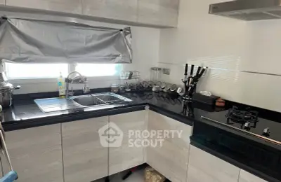 Modern kitchen with sleek black countertops and gas stove, featuring ample storage and natural light.