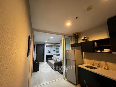 Modern apartment kitchen with sleek cabinets and cozy living area view.