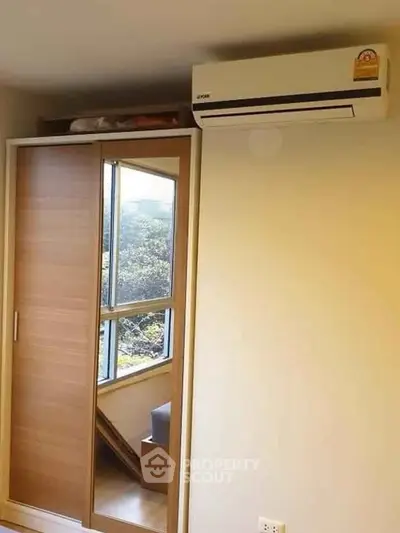 Modern bedroom with mirrored wardrobe and air conditioning unit