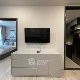 Modern living room with sleek TV setup and view into stylish bedroom