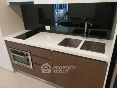 Modern kitchen with sleek cabinetry, dual sinks, and built-in oven in a stylish apartment.