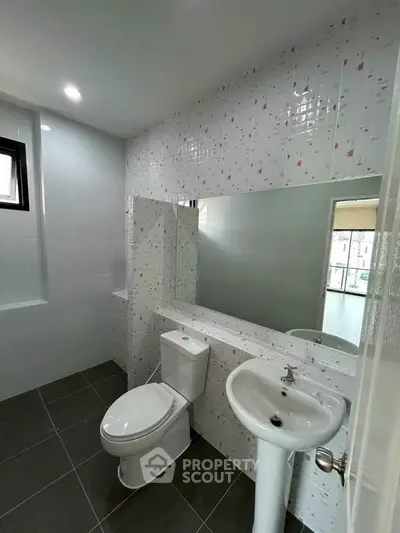Modern bathroom with sleek fixtures and large mirror, ideal for contemporary living.