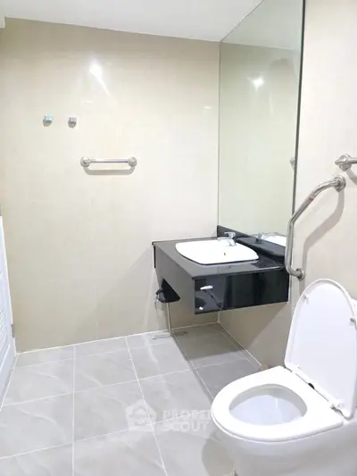 Modern bathroom with sleek fixtures and large mirror in a contemporary home.