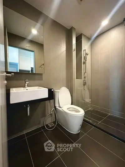 Modern bathroom with sleek design, featuring a glass shower and contemporary fixtures.