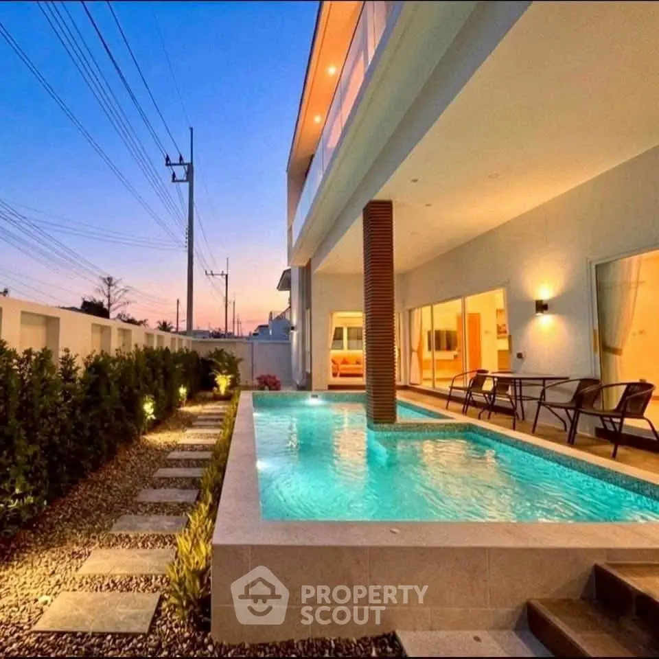 Luxurious modern home with stunning pool and elegant outdoor lighting at sunset.