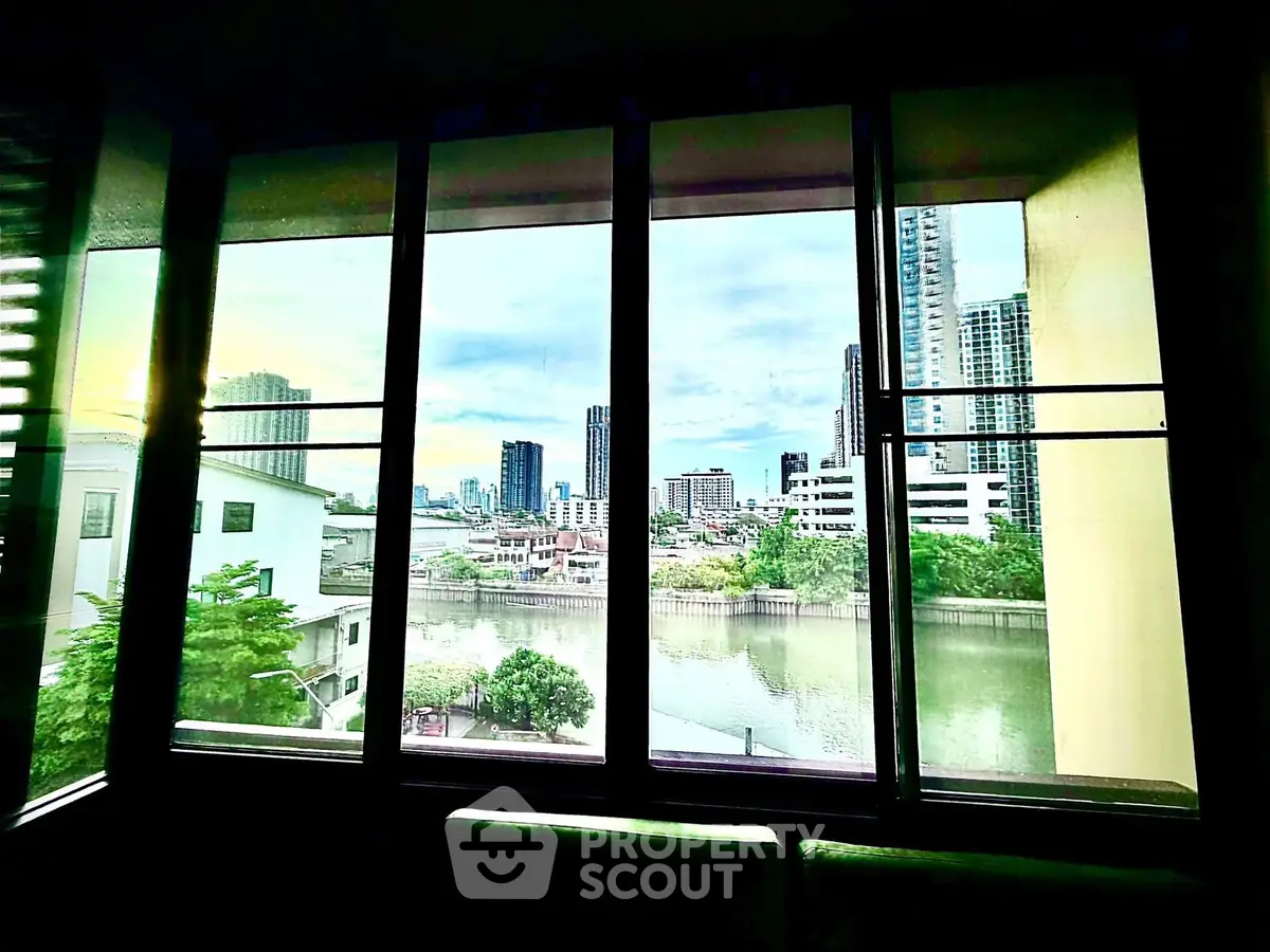 Stunning cityscape view from a modern apartment window overlooking a serene river.