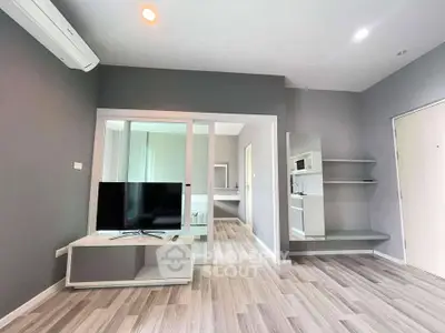 Modern living room with sleek design and open layout, featuring a TV and air conditioning.