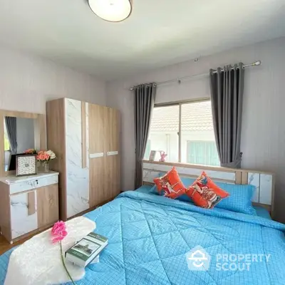 Cozy bedroom with large window, modern furniture, and vibrant blue bedding set against a neutral color palette for a serene living space.