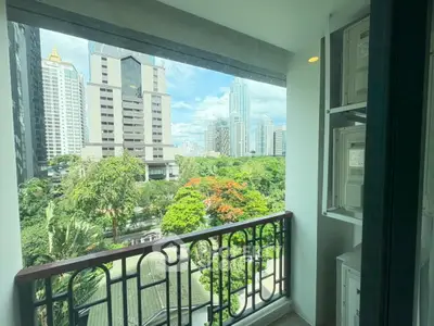 Stunning cityscape view from a modern balcony overlooking lush greenery and skyscrapers.