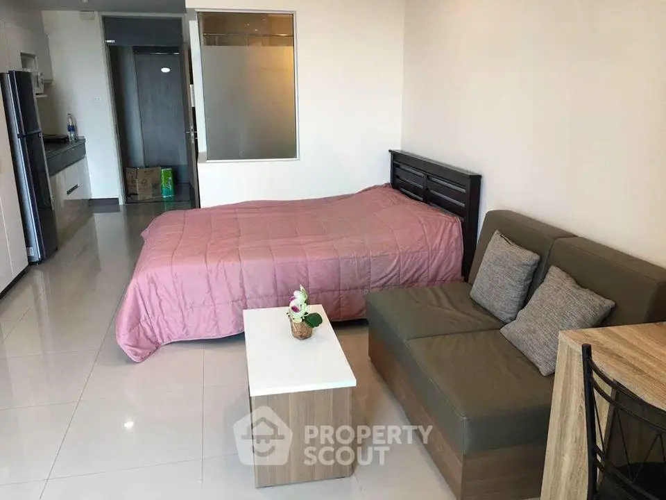 Modern studio apartment with cozy bed, compact kitchen, and stylish sofa in open layout.