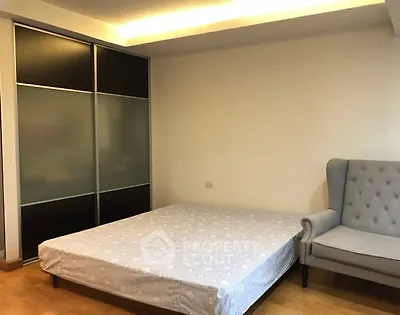 Spacious bedroom with modern sliding wardrobe and cozy armchair.