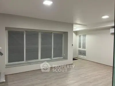 Spacious modern living room with large windows and sleek flooring, perfect for contemporary living.