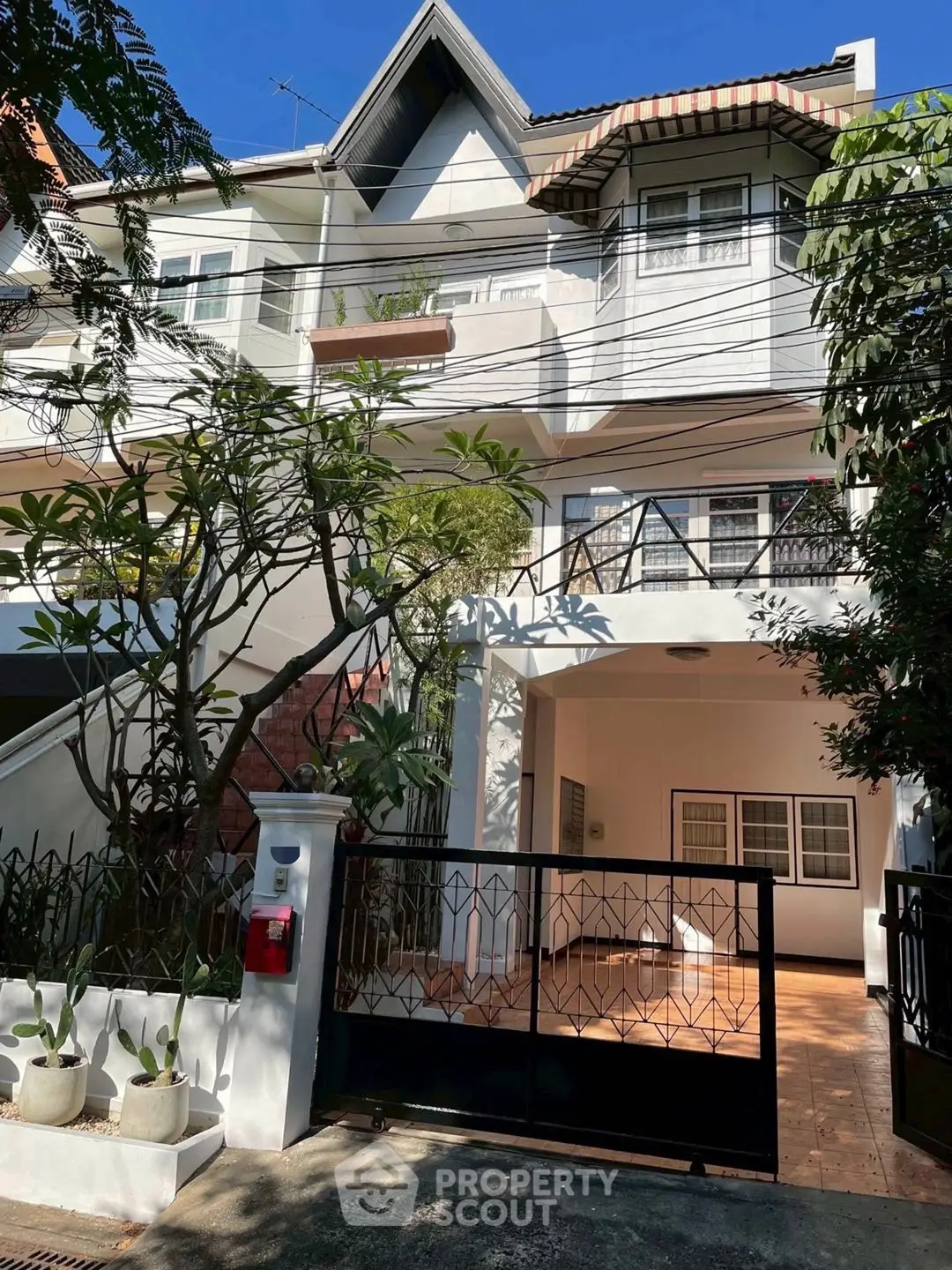 Charming multi-story townhouse with gated entrance and lush greenery, perfect for urban living.