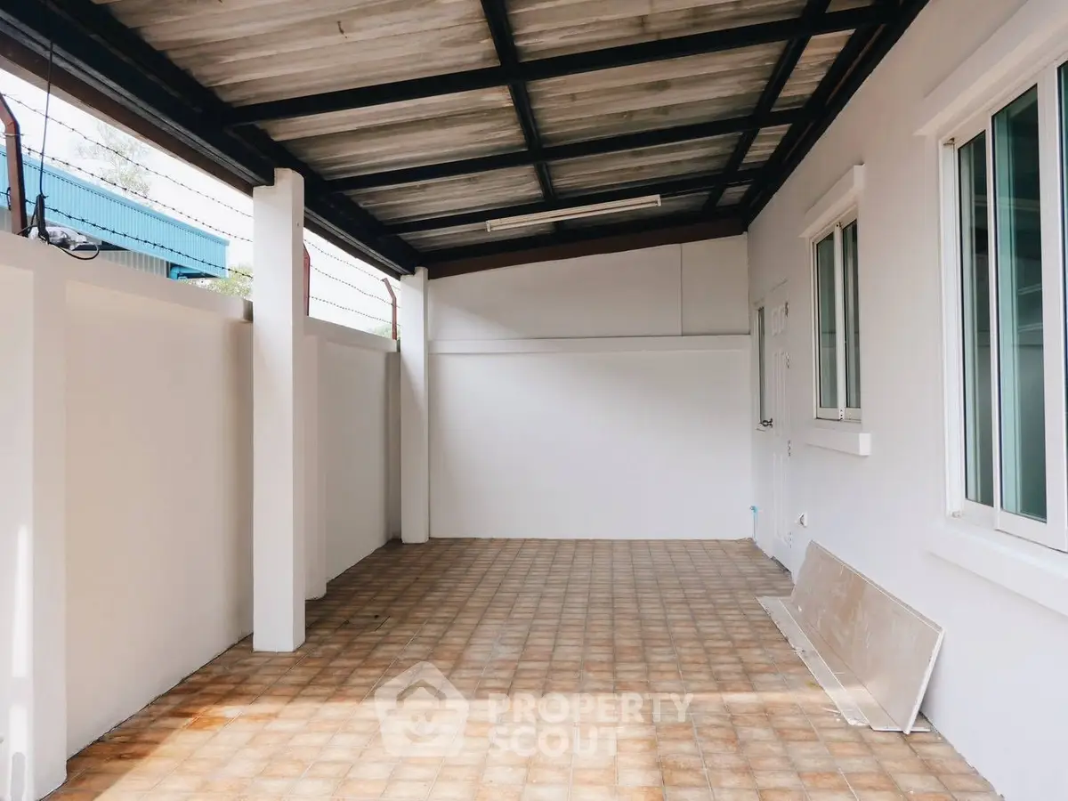 Spacious covered outdoor area with tiled flooring and white walls, perfect for versatile use.