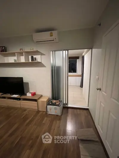 Modern living room with wooden flooring, air conditioning, and sliding door to adjacent room.