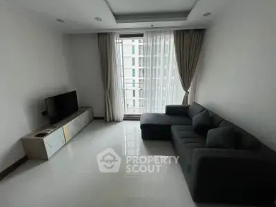 Modern living room with sleek furniture and large window offering natural light.