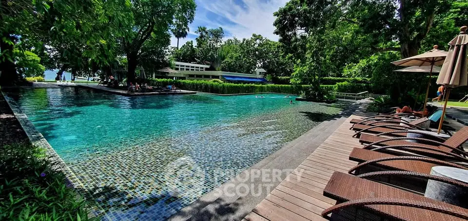 Luxurious outdoor pool area with lush greenery and sun loungers, perfect for relaxation and leisure.