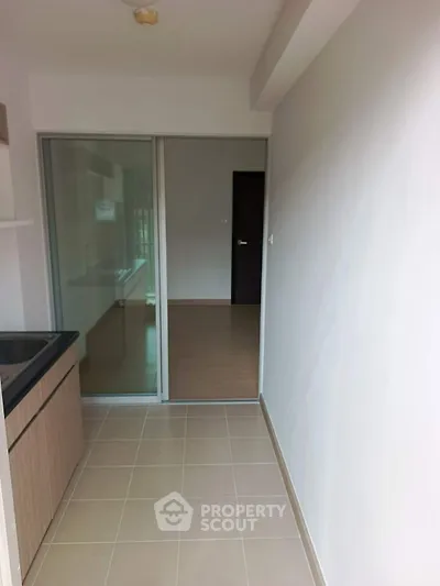 Modern kitchen with sleek design and sliding glass door leading to a spacious room.
