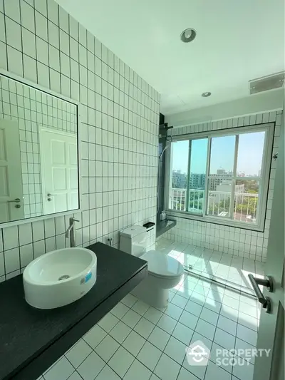 Modern bathroom with large window and city view, featuring sleek fixtures and stylish tile design.