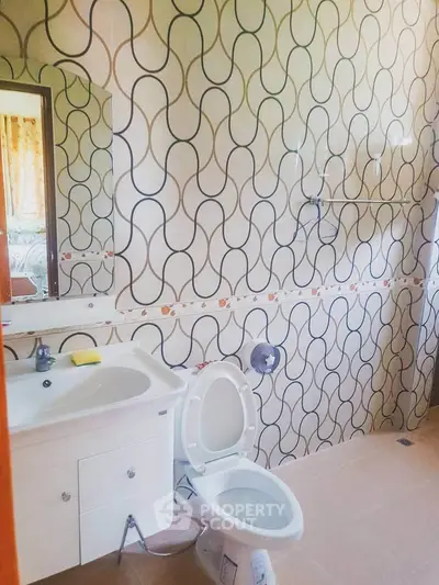 Spacious bathroom with modern sink and unique patterned wall tiles.