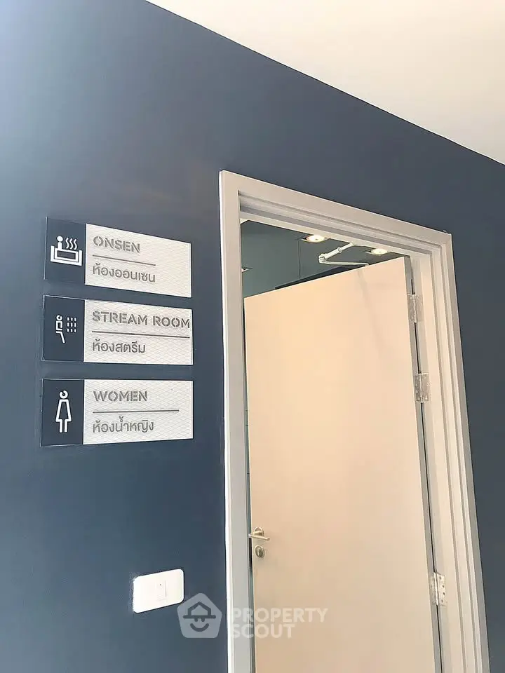 Modern building interior with signs for onsen, steam room, and women's restroom.