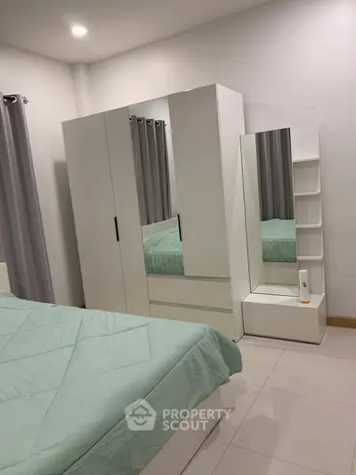 Modern bedroom with sleek white furniture and mint green bedding