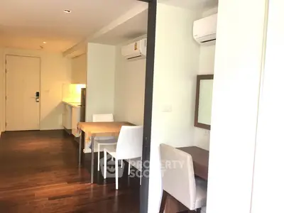 Modern apartment interior with dining area and workspace, featuring sleek design and air conditioning.