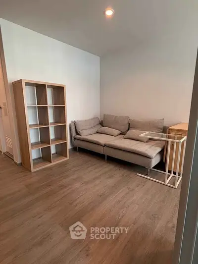 Modern living room with sleek wooden flooring and cozy gray sofa