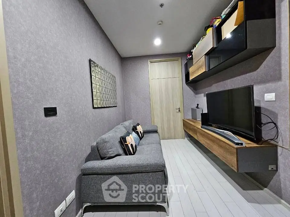 Modern living room with sleek grey sofa and wall-mounted TV unit in stylish apartment.