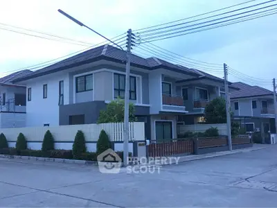 Modern two-story house with a fenced yard in a suburban neighborhood.