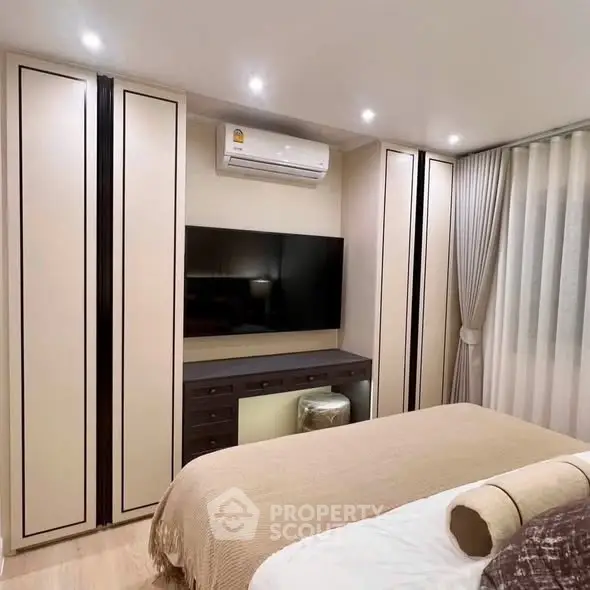 Modern bedroom with built-in wardrobe and wall-mounted TV, featuring elegant lighting and cozy decor.