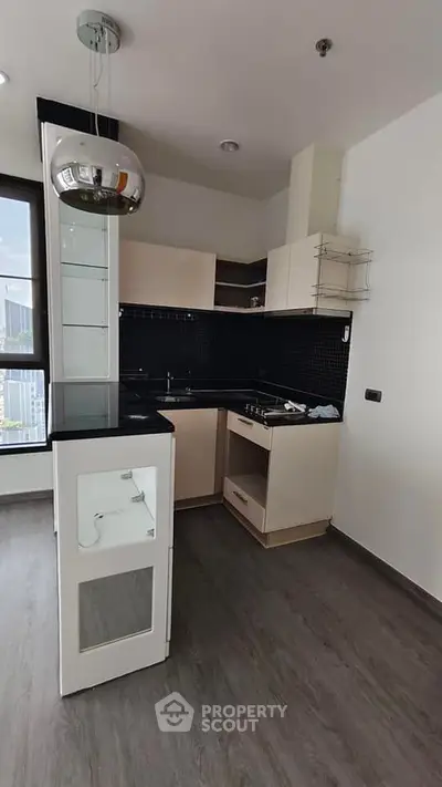 Modern kitchen with sleek black backsplash and compact design in urban apartment.