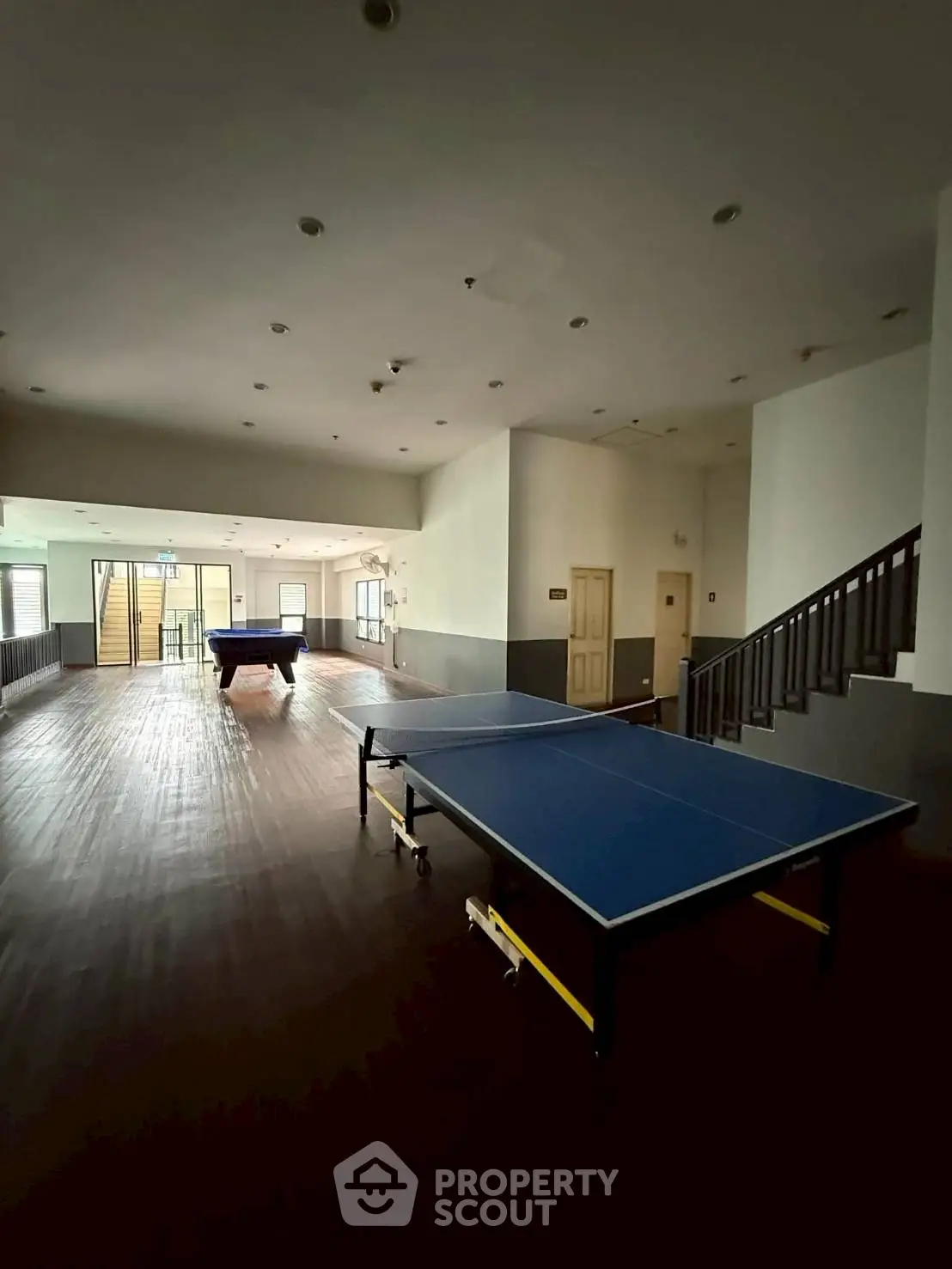 Spacious recreational area with table tennis and pool table in modern building.