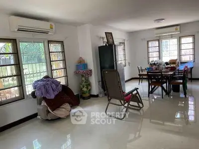Spacious living room with dining area, large windows, and air conditioning in a cozy home.