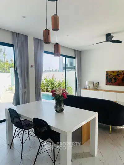 Modern dining area with pool view, featuring elegant decor and natural light.