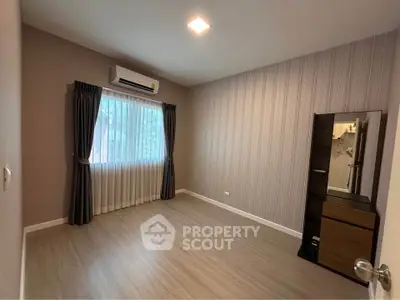 Spacious empty bedroom with wooden flooring and large window, perfect for customization.