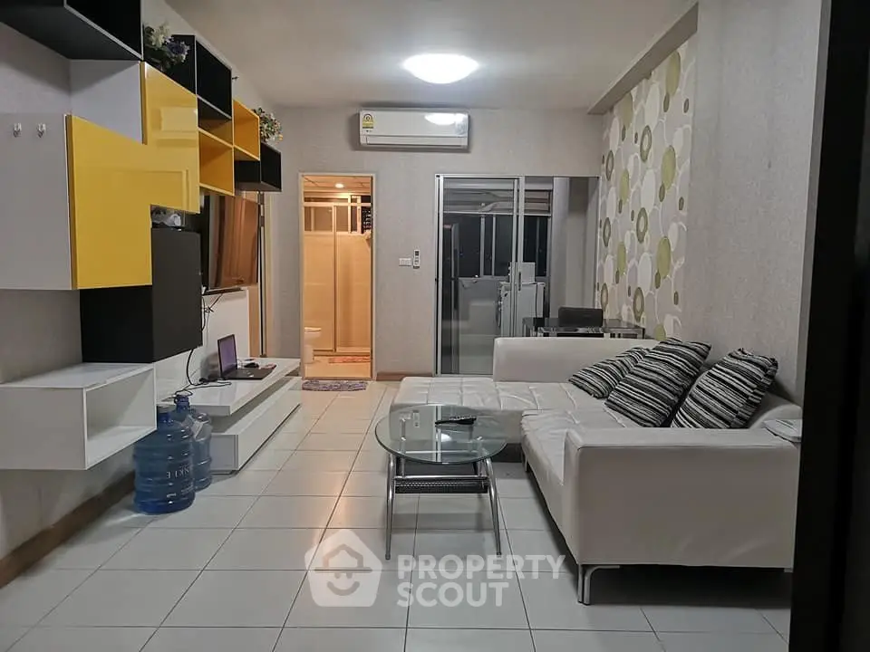 Modern living room with stylish furniture and open layout, featuring a sleek white sofa and vibrant shelving.