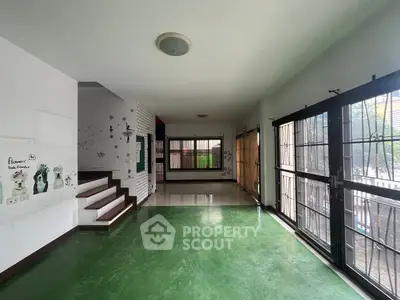 Spacious open-plan living area with green flooring and large windows