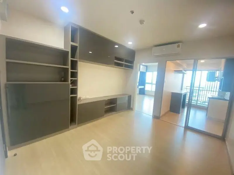 Modern living room with built-in shelving and sliding glass doors leading to a balcony.