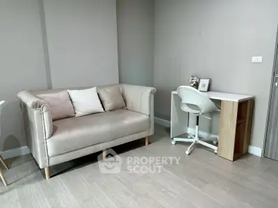 Modern living room with stylish sofa and compact study desk in a cozy apartment.