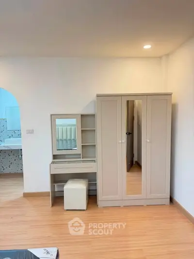 Spacious bedroom with elegant wardrobe and vanity set, featuring modern design and ample storage.