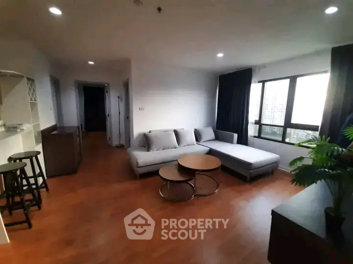 Spacious living room with modern furniture and large windows offering city views.