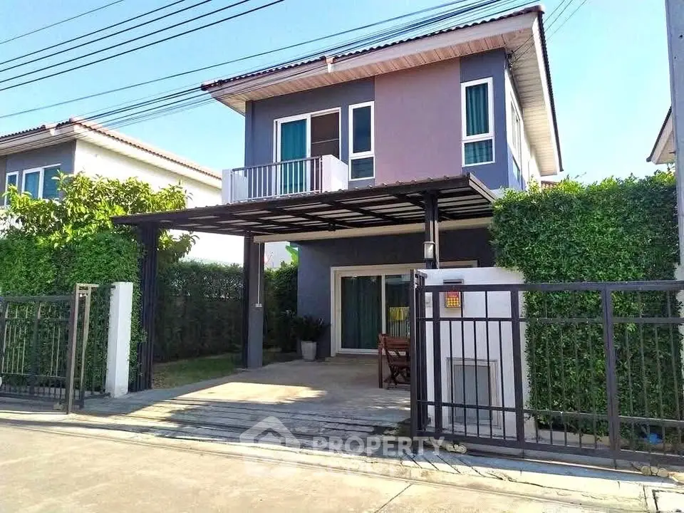 Modern two-story house with balcony and gated driveway in a suburban neighborhood.
