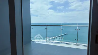 Stunning ocean view from modern balcony with glass railing and clear blue skies.