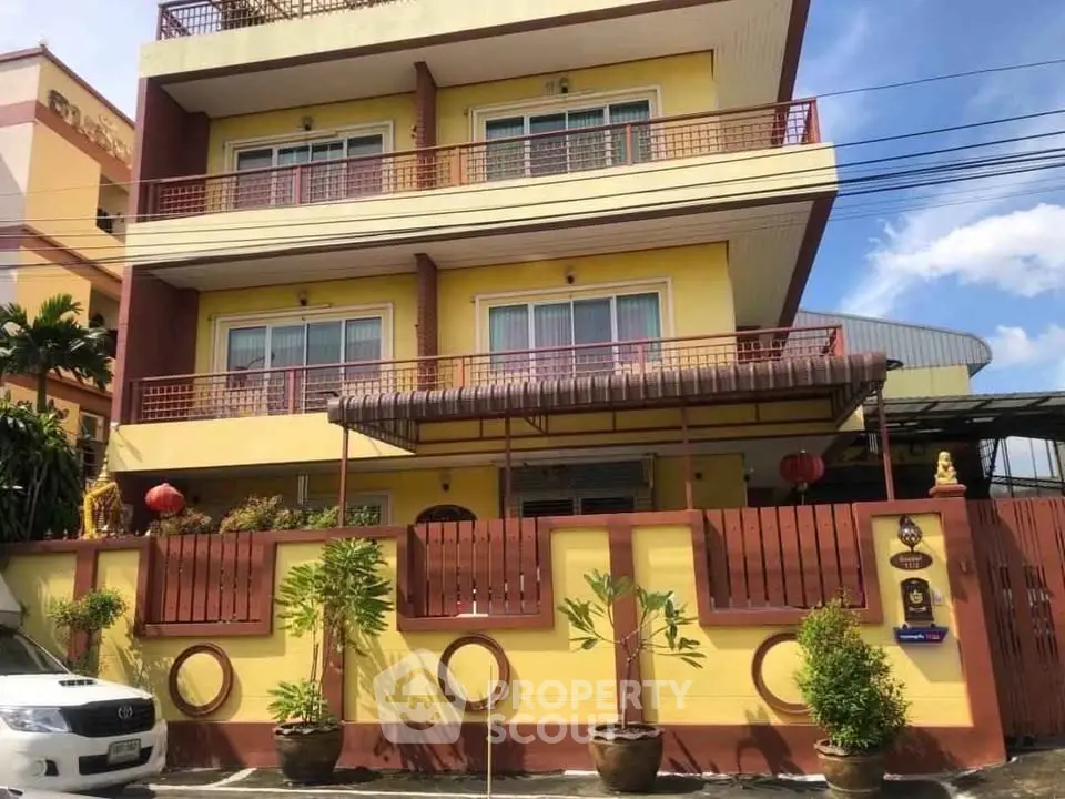 Charming three-story building with vibrant yellow facade and decorative balcony railings.